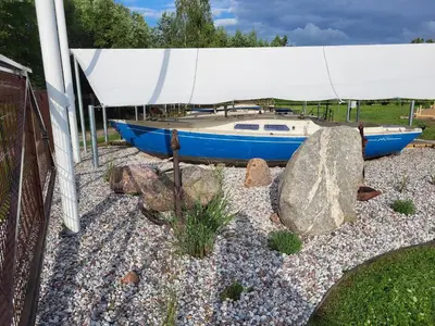 a blue boat sitting on top of a pile of rocks at Uždubysio baidarės Nakvynė Jachtose (Night on a Yacht) in Ariogala