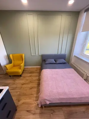 a bedroom with a bed and a yellow chair at 22 Airport Apartment in Vilnius