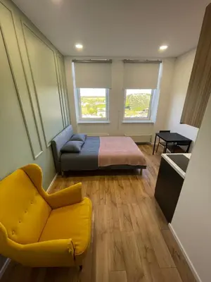a bedroom with a bed and a yellow chair at 22 Airport Apartment in Vilnius