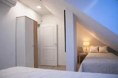 a attic bedroom with two beds and a door at Gallery Balta Apartments in Kaunas