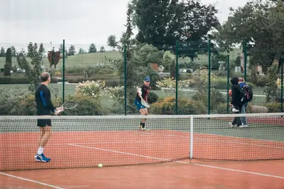 a group of men playing tennis on a tennis court at Royal Horse Resort in Balkasodis