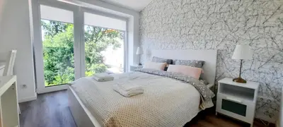 a white bedroom with a large bed and a window at Fortress Stay in Kaunas
