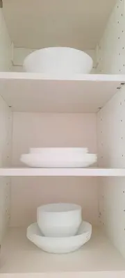 a shelf with white bowls and plates on it at Fortress Stay in Kaunas