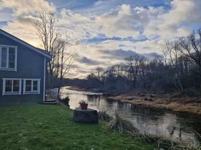 a house next to a river next to a house at Šušvė in Plinkaigalis
