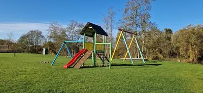 a playground with a slide and a swing set in a field at Šušvė in Plinkaigalis