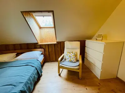 a bedroom with a bed and a chair with a window at Forest springs. Family vacation tennis beach sauna in GratiÅ¡kÄ—s