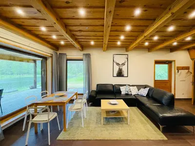 a living room with a black leather couch and a table at Forest springs. Family vacation tennis beach sauna in GratiÅ¡kÄ—s