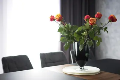 a vase with roses in it sitting on a table at Koala rest house in Druskininkai
