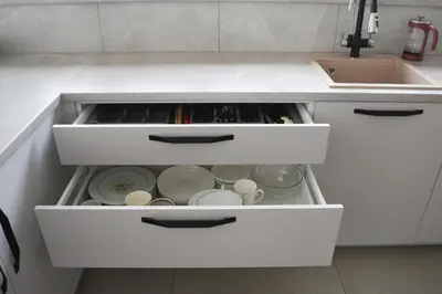 a kitchen with white drawers with dishes and a sink at Koala rest house in Druskininkai