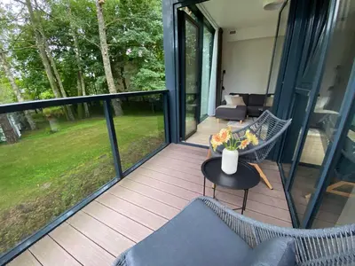 a screened in porch with a vase of flowers on a table at Apartment-Pine Forest Birštonas in Birštonas