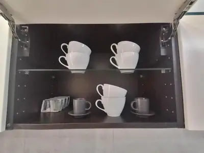 a shelf with cups and tea cups on it at Erdvi studija Spacious studio apartment Self check in in Vilnius