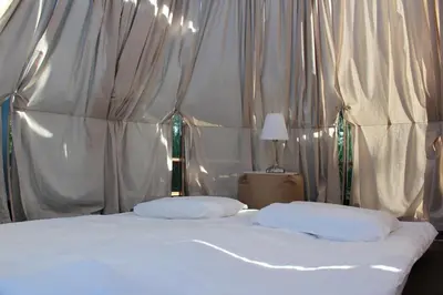 a bed with white sheets and pillows in a tent at Vila Ula in Perloja