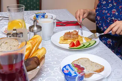 a table with plates of food and a person eating food at Vila Ula in Perloja