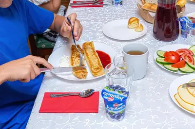 a person eating food on a table with plates of food at Vila Ula in Perloja