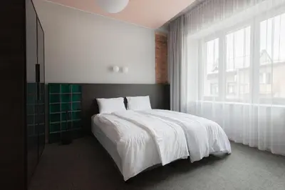 a bedroom with a white bed and a large window at Resume apartments in Kaunas