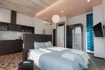 a bedroom with a large bed and a kitchen at Resume apartments in Kaunas