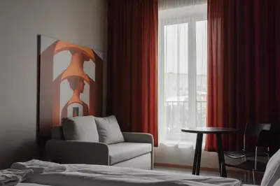a bedroom with a couch and a chair and a window at Resume apartments in Kaunas