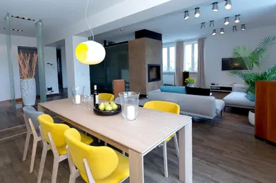 a dining room and living room with a table and yellow chairs at Vilnius Apartments & Suites - Gedimino avenue in Vilnius