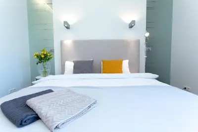 a bedroom with a large white bed with orange and gray pillows at Vilnius Apartments & Suites - Gedimino avenue in Vilnius