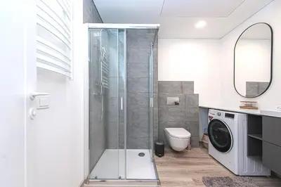 a bathroom with a shower and a washing machine at Paupys Central Apartments by Reside Baltic in Vilnius