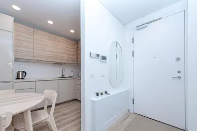 a white kitchen with a table and a dining room at Paupys Central Apartments by Reside Baltic in Vilnius