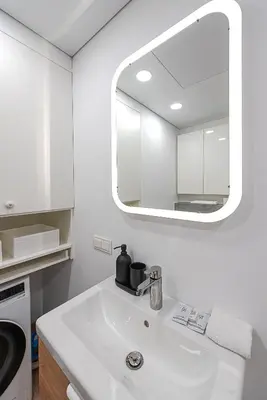 a white bathroom with a sink and a mirror at Paupys Central Apartments by Reside Baltic in Vilnius
