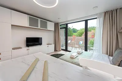 a white bedroom with a large window and a television at Paupys Central Apartments by Reside Baltic in Vilnius