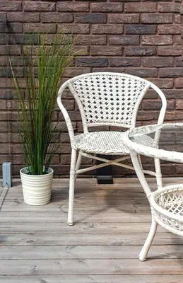 a white wicker chair sitting next to a plant at Paupys Central Apartments by Reside Baltic in Vilnius