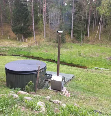 an outdoor stove with a tub in a field at Ramintos miško namelis in Žiogeliai