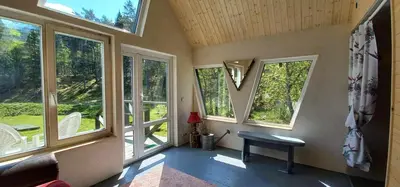 a room with windows and a bench and a table at Ramintos miško namelis in Žiogeliai