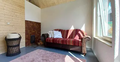 a living room with a couch and a window at Ramintos miško namelis in Žiogeliai