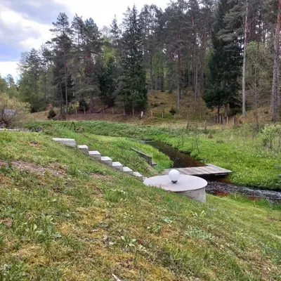 a stone bench sitting on the side of a field at Ramintos miško namelis in Žiogeliai