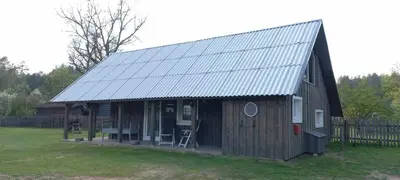 a large wooden building with a metal roof at Ramintos miško namelis in Žiogeliai