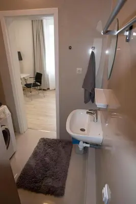 a white bathroom with a sink and a mirror at Main Street Šiauliai, City Center in Šiauliai