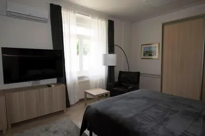 a bedroom with a bed and a tv and a chair at Main Street Šiauliai, City Center in Šiauliai