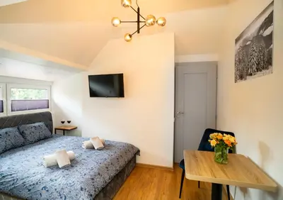 a bedroom with a bed and a table and a tv at Fort63 apartments in Kaunas
