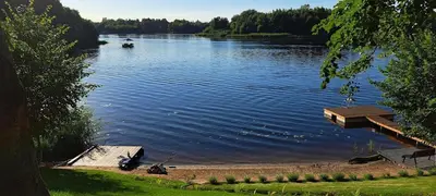 a lake with a dock and a boat in the water at Namelis po beržais in Marijampolė