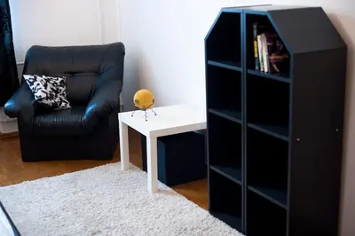 a black bookcase with a white table and a chair at V 13 - 3 BDR Balcony, Views - Courtyard n Vokiečių in Vilnius