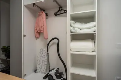 a closet with white shelves and a vacuum at Nordic Studio In Prime Vilnius Location in Vilnius