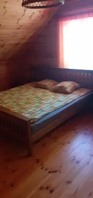 a bed in a wooden cabin with a window at Vila Mera in Pabradė