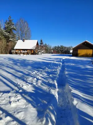 a snow covered road with a house in the background at Vila Mera in Pabradė