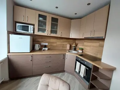 a kitchen with wooden cabinets and a white refrigerator at Patogus poilsis prie ežero/Comfortable rest in Visaginas