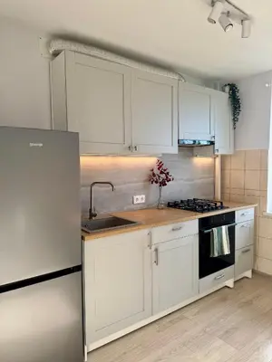 a kitchen with white cabinets and a sink at Rokiskis- jaukus butas su balkonu in Rokiškis
