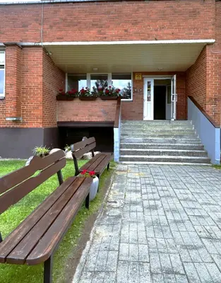 a wooden bench sitting in front of a brick building at VESK Veisiejai in Veisiejai