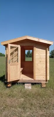 a wooden shed in the middle of a field at Bičių namas Bičių lova Bee house in Sargeliai