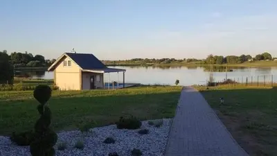 a house on the side of a lake with a walkway at Pirties namelis in Girininkai