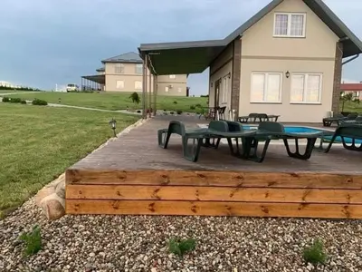 a patio with picnic tables and chairs in front of a house at Pirties namelis in Girininkai