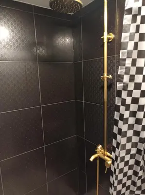 a bathroom with a shower with black and white tiles at Comfort Akacija Hotel in Vilnius