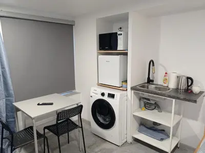 a laundry room with a washing machine and a table at Comfort Akacija Hotel in Vilnius