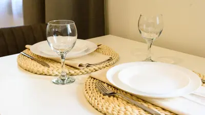 a table with two wine glasses and plates on it at Karaliaus apartment in Kaunas